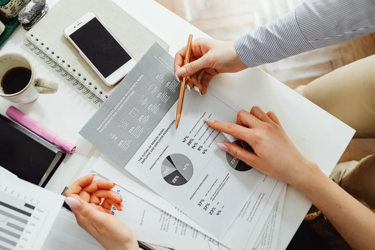 Two people reviewing printed charts and reports at a desk