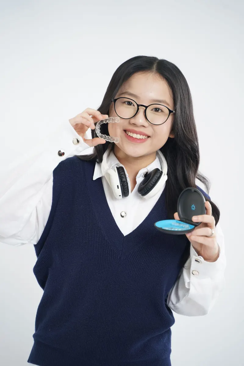 Smiling woman holding clear aligners