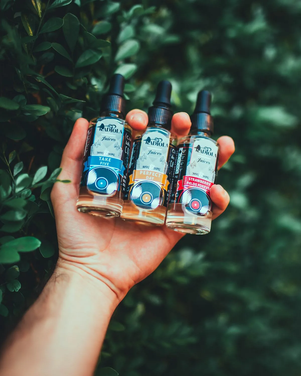 Hand holding three e-liquid bottles